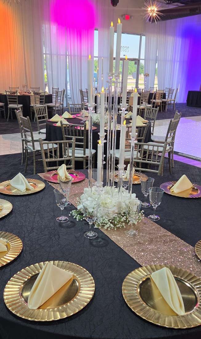 Round banquet tables in black linen with champagne sequin runners and gold charger plates at Silverstar Event Center in Lewisville, TX