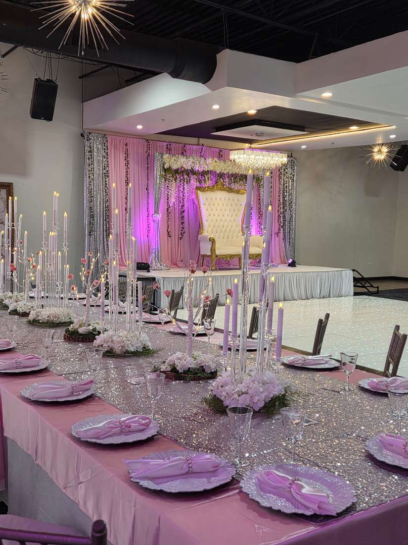 A long head table in blush satin and silver sequin with pink chargers and tall candelabras at Silverstar Event Center in Lewisville, TX