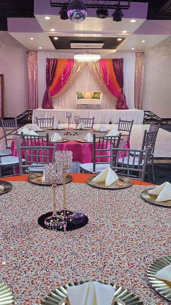 A fuchsia, orange and gold draped stage with an ivory sofa at Silverstar Event Center in Lewisville, TX