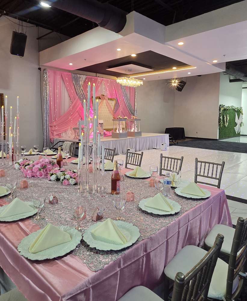 A mauve and silver sequin head table lined with pink roses and tall white candelabras at Silverstar Event Center in Lewisville, TX