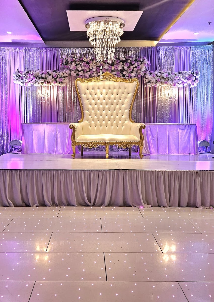 Ivory tufted throne loveseat on stage beneath silver starburst chandeliers at Silverstar Event Center in Lewisville, TX